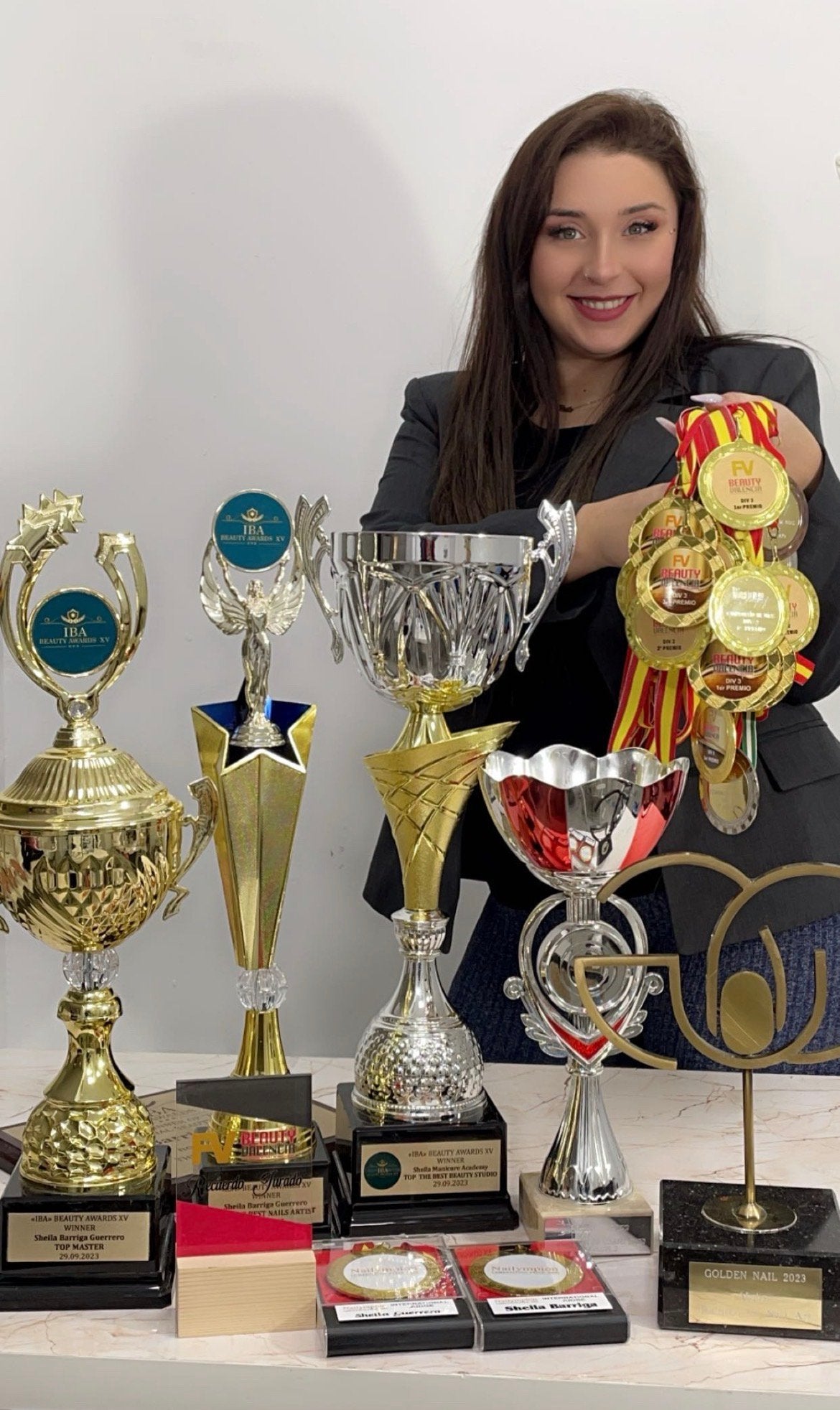 Sheila Barriga, fundadora de Sheila Manicure Academy, rodeada de sus trofeos de campeonatos internacionales de uñas